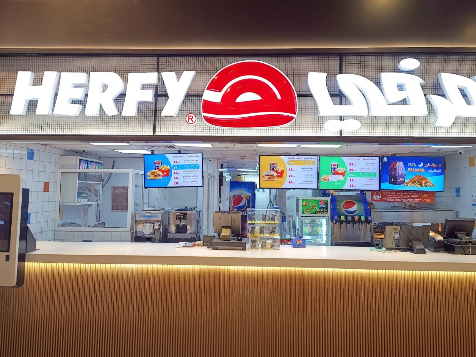 A Herfy counter with four menuboards, the last one advertising Volcano fries