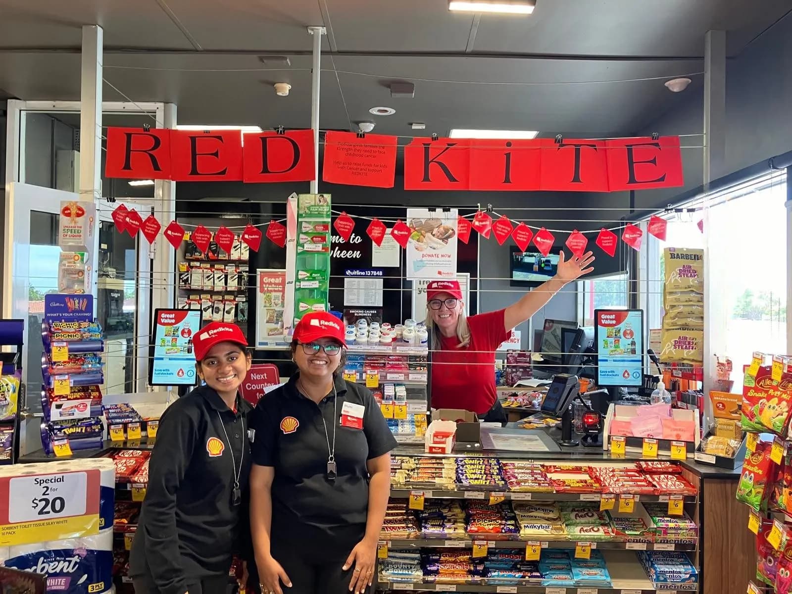 Reddy Express staff at the counter, with OmmaSign promotions on the customer-facing POS screens either side