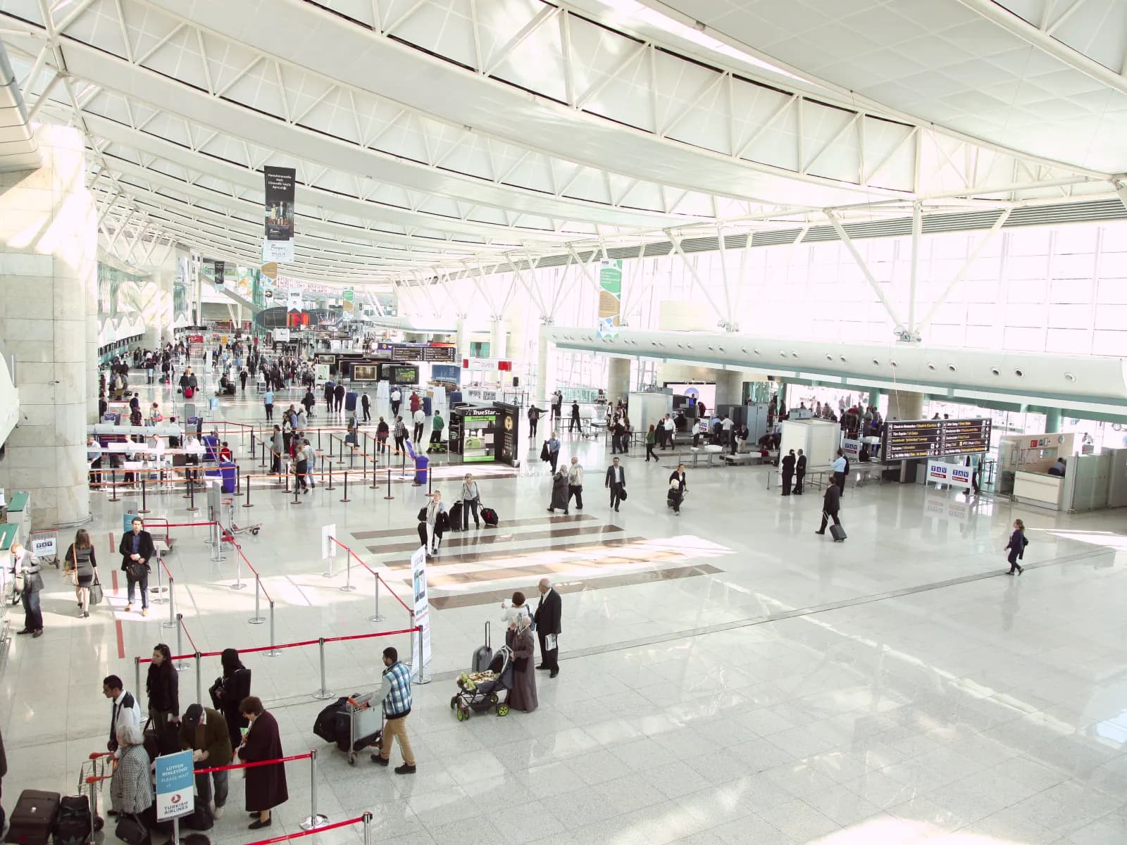 The departures hall at Ankara Esenboğa, with passengers queuing at check-in under the steel roof