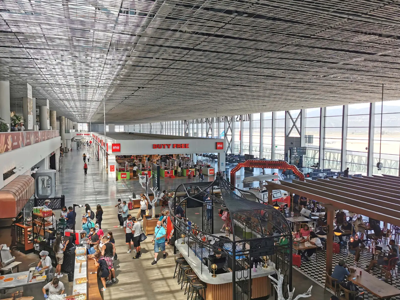 The departures area at Milas-Bodrum Airport, with the duty-free shop and food court under a long glass wall