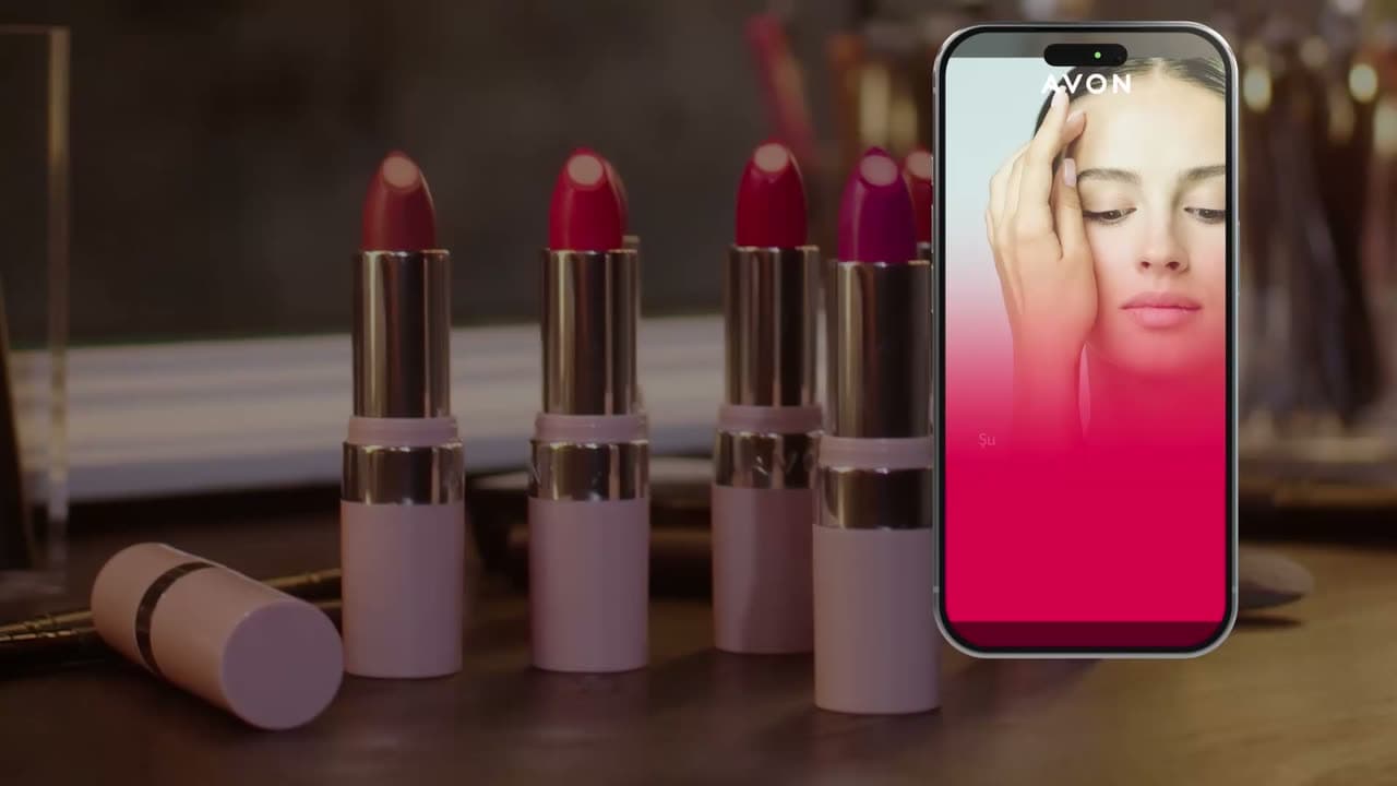 Avon lipsticks on a table beside a phone playing a representative's personalized video