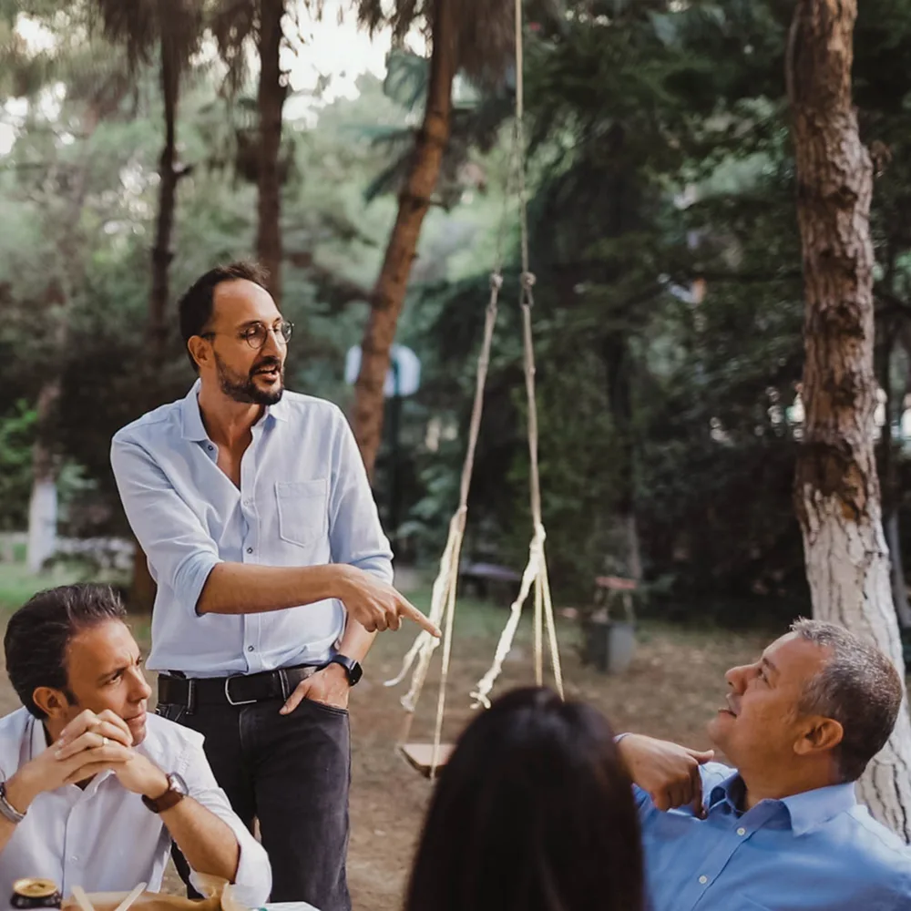 An OmmaWorks team member speaking with colleagues around an outdoor table